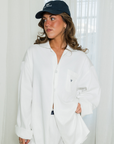 Woman wearing a white shirt and navy cap indoors with light background