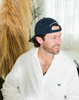 Man wearing a navy cap and white shirt sitting indoors