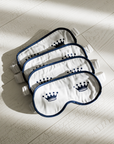 Four sleep masks with a crown logo on a light wooden floor
