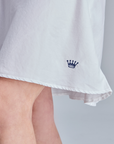White skirt with a blue crown logo on a neutral background
