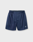 A pair of navy blue boxer shorts with an elastic waistband and a small white crown logo on the lower left leg, displayed against a light gray background.