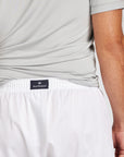 Close-up of a person wearing white shorts with a navy waistband label reading 'Royal Highnies' and a light gray T-shirt