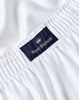 Close-up of white elastic-waist fabric with a dark navy brand label reading Royal Highnies and a small crown logo.