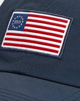 Navy blue cap with a patch featuring an American flag design on a plain background