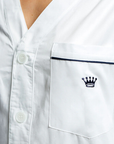 Close-up of a white shirt with a crown logo on the chest pocket.