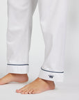 White pajama pants with dark navy piping along the cuffs and a small navy crown logo on one cuff.