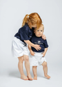 Two children wearing navy blue shirts with white text on a light gray background