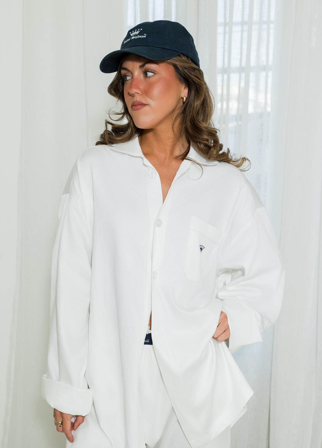 Woman wearing a white shirt and navy cap indoors with light background