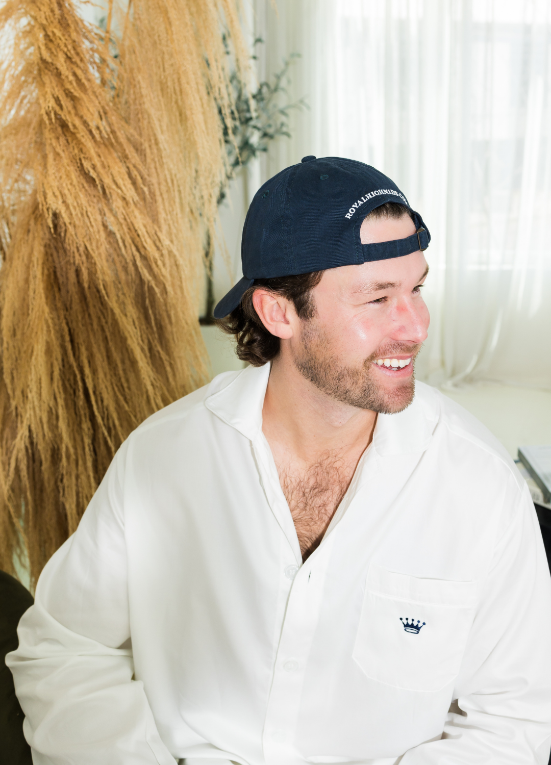 Man wearing a navy cap and white shirt sitting indoors