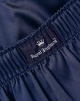 Close-up of dark navy blue gathered fabric with an elastic waistband and a sewn-in label reading Royal Highnies with a white crown logo.