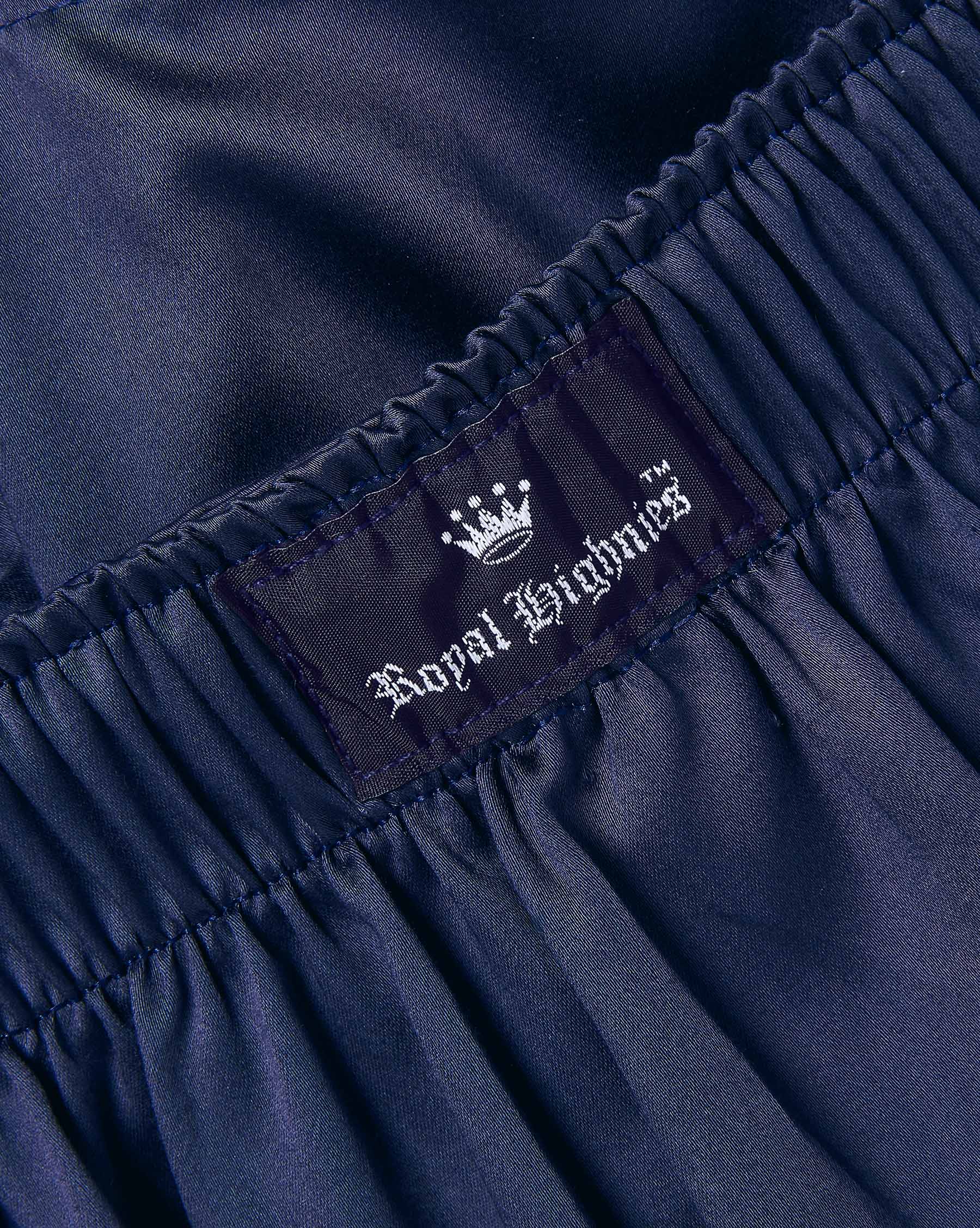 Close-up of dark navy blue gathered fabric with an elastic waistband and a sewn-in label reading Royal Highnies with a white crown logo.
