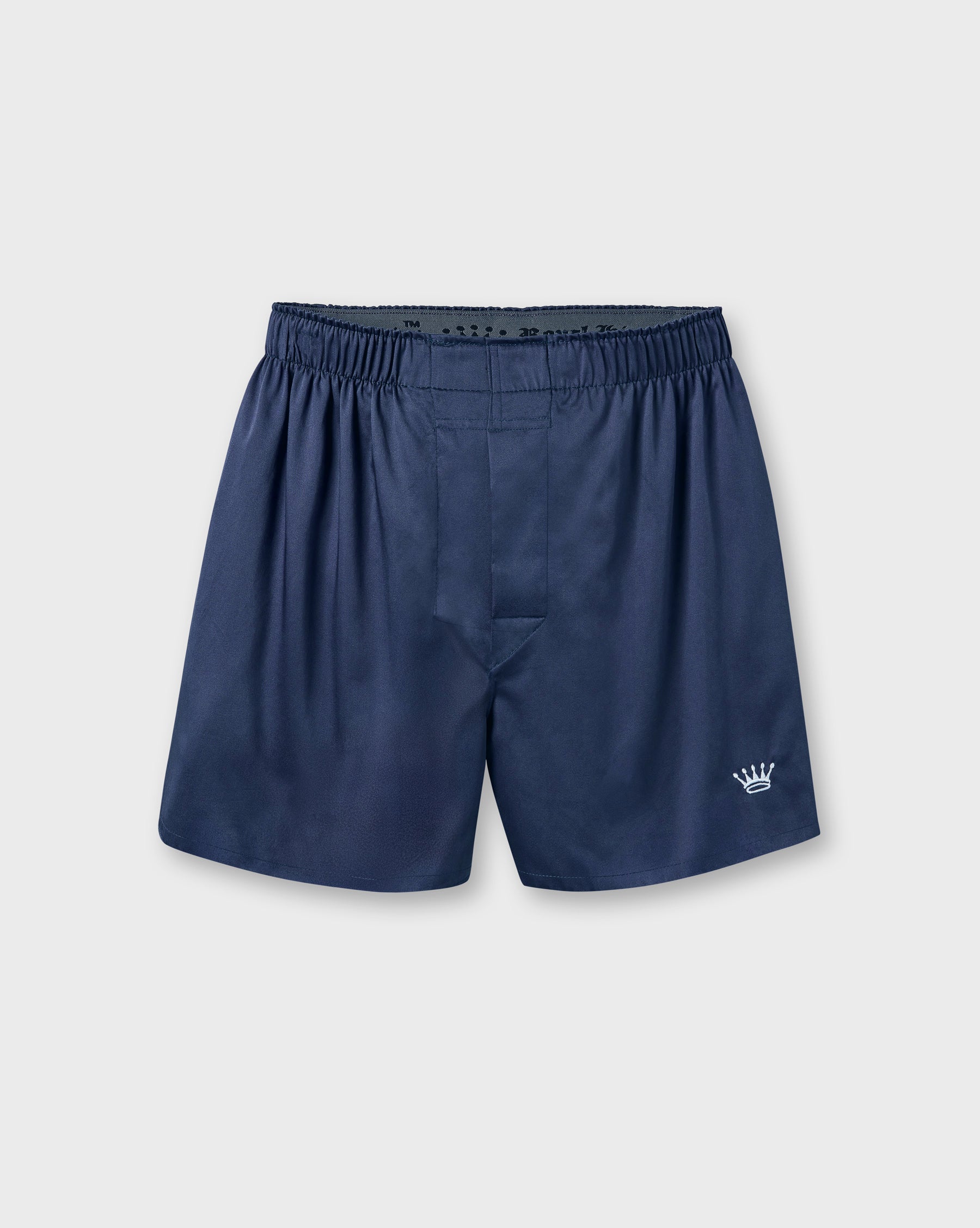 A pair of navy blue boxer shorts with an elastic waistband and a small white crown logo on the lower left leg, displayed against a light gray background.