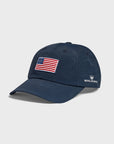 A navy baseball cap featuring an embroidered American flag patch on the front and the Royal Highnies logo embroidered in white on the side.