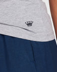 Close-up of a light gray athletic top with a small navy embroidered crown logo, worn over dark navy shorts.