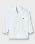 A white long-sleeve button-up shirt with a collar, a chest pocket, and a small navy blue crown logo embroidered on the pocket, displayed against a light gray background.