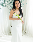Woman in a white night gown holding a flower in front of white curtains