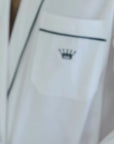 Short video clip of a person in a white robe adjusting pillows on a bed in a minimalistic room.