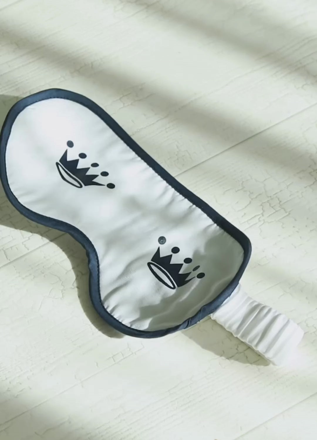 Short video clips showing a white sleep mask with two navy crown logos