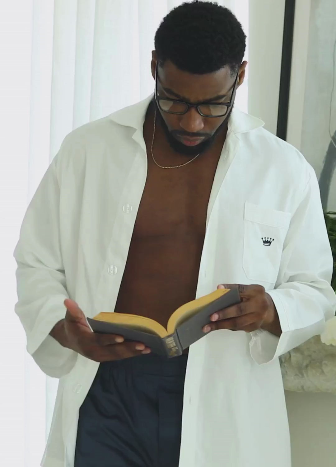 Short video clip showing a man wearing navy blue boxers and a white top while reading.