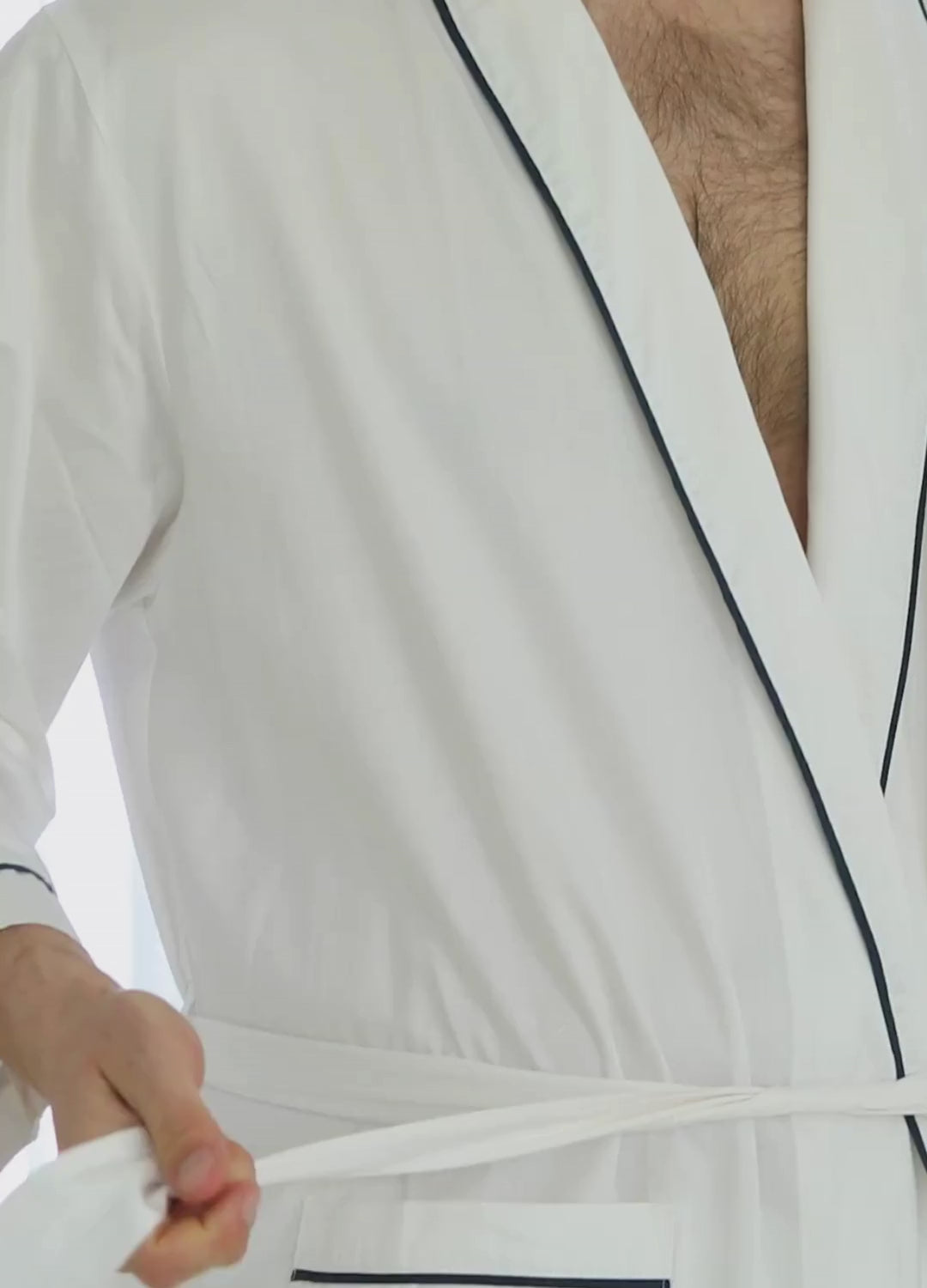 Short video clip showing a man wearing a white robe with a navy crown logo on the chest area