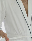 Short video clip showing a man wearing a white robe with a navy crown logo on the chest area