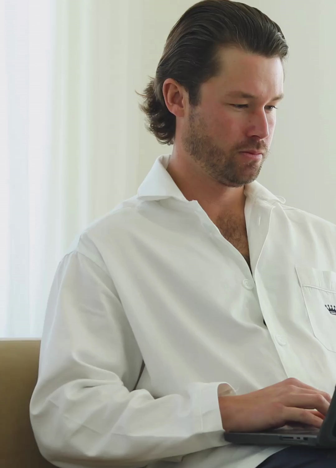 Short video clip showing a man wearing a white button-up shirt working on a laptop
