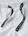 Close-up of white drawstring shorts with a button front and dark navy drawstrings printed with white text reading 'Royal Highnies' and a crown logo.