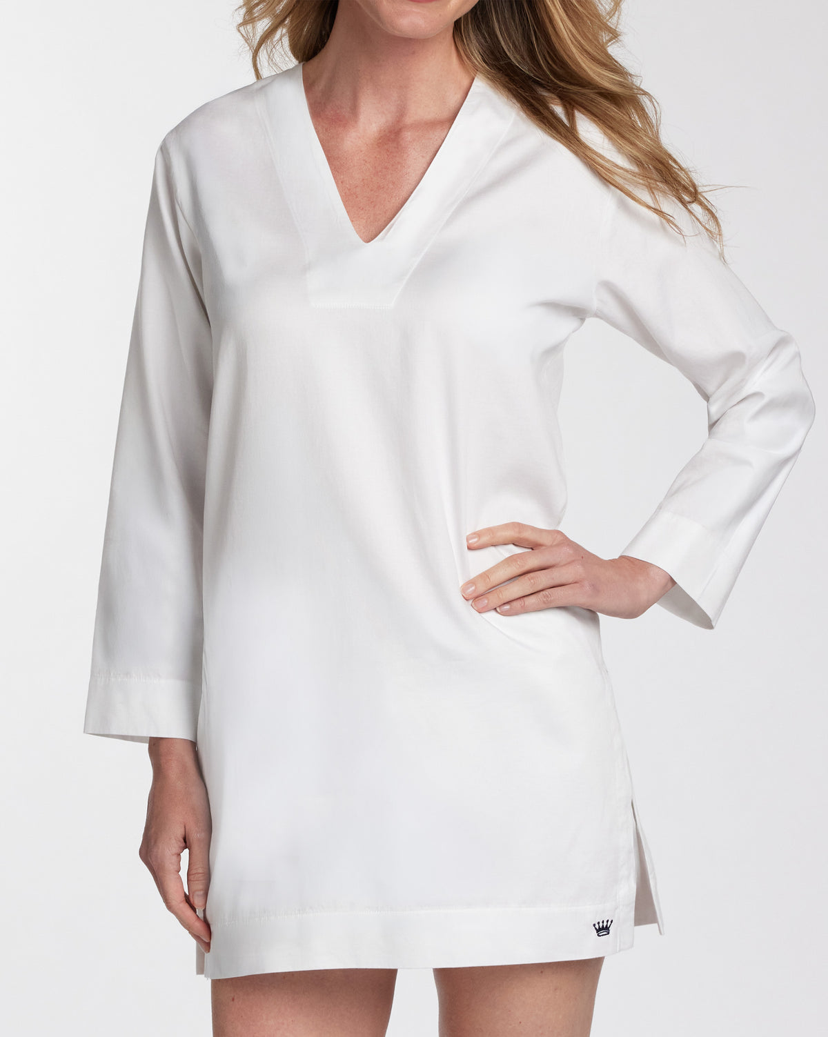 A woman wearing a white long-sleeve V-neck tunic-style top with a relaxed fit, shown against a plain light background.